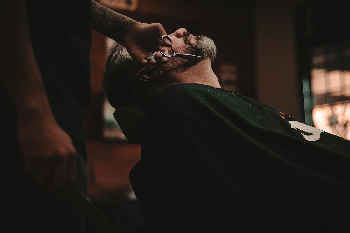 A barber shaping a client’s beard, illustrative photograph